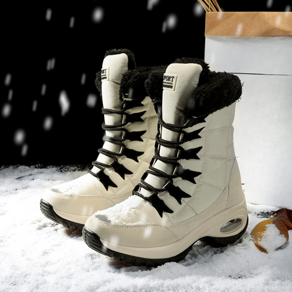 Beige winterlaarzen met zwarte veters en bontvoering, geschikt voor sneeuw. Comfortabele, warme dameslaarzen voor koude weersomstandigheden.