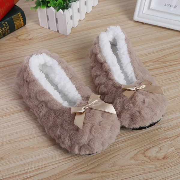 Pluche damespantoffels in beige met witte voering en strikje, comfortabel en warm, perfect voor thuisgebruik. Ideaal voor koude winterdagen.
