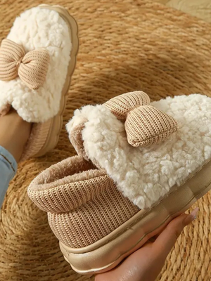 Pluche pantoffels met strik, beige kleur, op ronde gevlochten mat. Comfortabele dames sloffen, warme wintermode, trendy huisstijl.