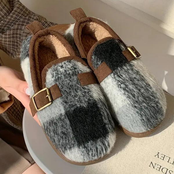 Zwart-witte wollen pantoffels met bruine gespen, geruit patroon en zachte voering, perfect voor wintercomfort en stijl.