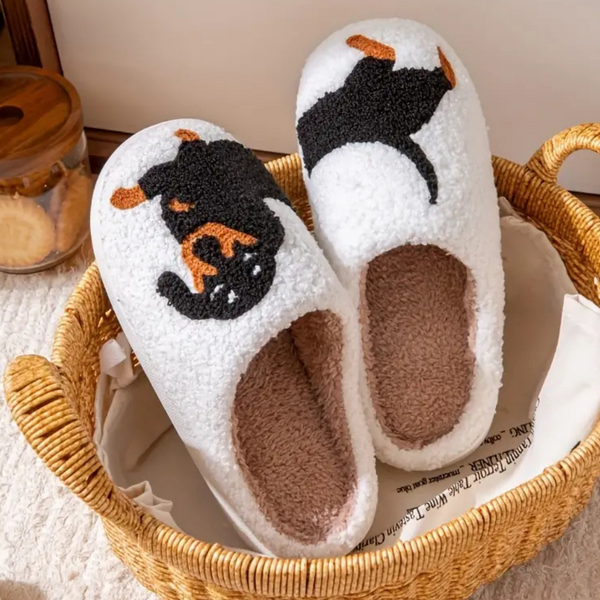 Witte pluche pantoffels met Rottweiler-patroon in een rieten mand. Comfortabele, warme slippers voor thuisgebruik. Perfect voor hondenliefhebbers.
