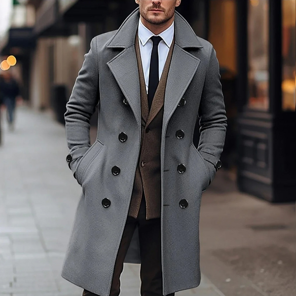 Stijlvolle man in grijze wollen overjas, dubbele rij knopen, formele kleding, stadsstraat. Herfstmode, herenmode, elegante jas.