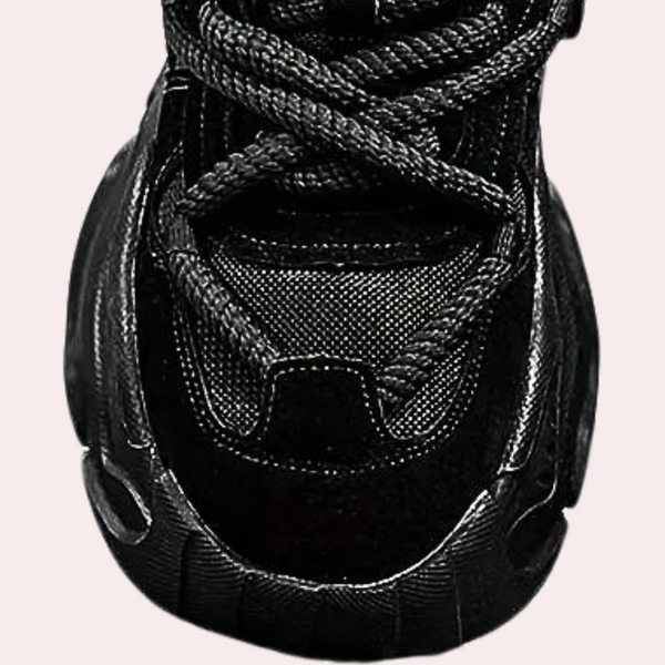 Zwarte sneaker met dikke zool en gedetailleerd stiksel, sportief design, bovenaanzicht. Perfect voor casual en sportieve outfits.