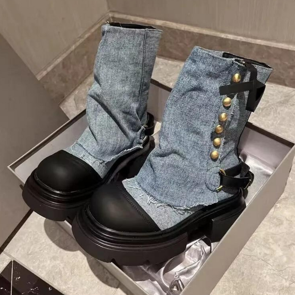 Blauwe denim laarzen met zwarte rubberen zolen, gouden knopen en decoratieve strik, in een doos op een marmeren vloer. Trendy damesmode.