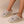 Grijze pluche pantoffels met kattenoortjes en groene ogen, gedragen door een persoon. Comfortabele, warme slippers voor binnengebruik.