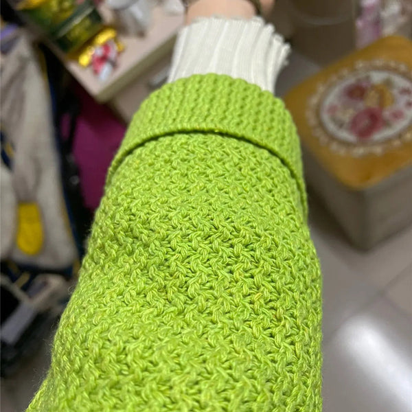 Groene gebreide mouw van een trui, close-up. Textuur en patroon duidelijk zichtbaar. Modieuze winterkleding, trendy gebreide stof.