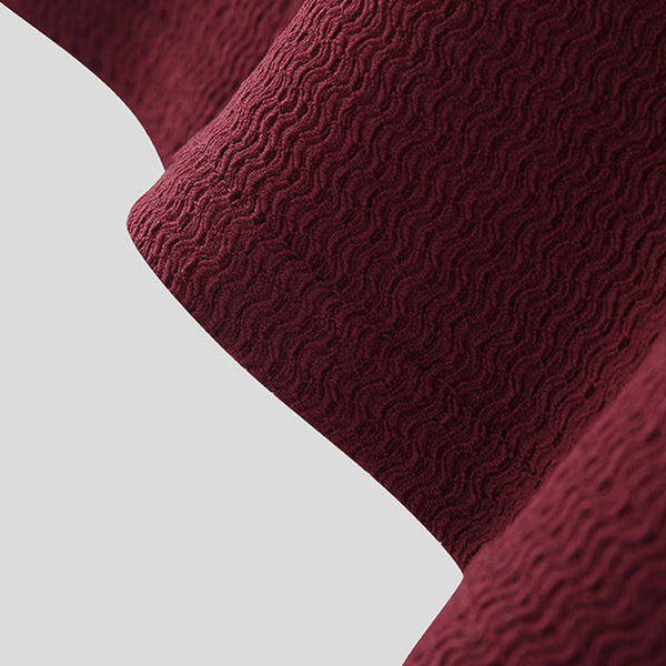 Bordeauxrode stof met golvend patroon, close-up. Textieltextuur, interieurdecoratie, hoogwaardige stof voor meubels of gordijnen.