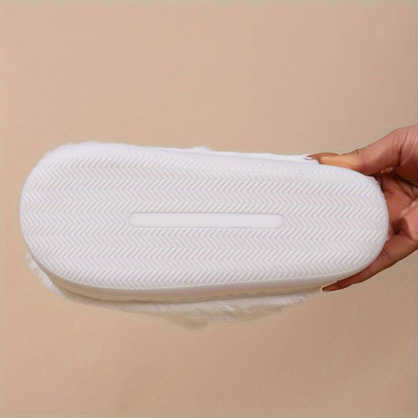 Witte rubberen zool van een slipper met visgraatpatroon, vastgehouden door een hand. Comfortabele, duurzame slippers voor dagelijks gebruik.