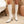 Witte gebreide kniehoge soklaarzen met hoge hakken, gestyled in een moderne interieursetting. Trendy damesmode, herfst/winter schoenen.