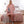 Vrouw in roze oversized hoodie deken staat in slaapkamer, naast bed met roze dekbedovertrek. Comfortabele, warme kleding voor thuis.