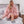 Vrouw in roze oversized fleece hoodie deken zit op bed, comfortabele loungewear, knusse wintermode, zachte huiselijke sfeer, grijze sokken.