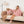 Vrouw en hond in roze fleece hoodies op bank, moderne woonkamer, vloerlamp, beige deken, comfortabele slippers, huiselijke sfeer.