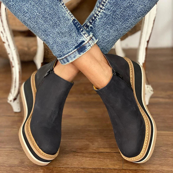 Zwarte enkellaarzen voor dames met dikke zool, gedragen met blauwe jeans. Trendy en comfortabele schoenen, perfect voor casual outfits.