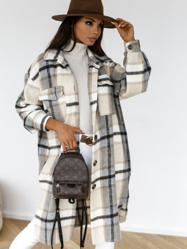 Vrouw in geruite jas en hoed met designer rugzak, modieuze winterlook, stijlvolle dameskleding, trendy accessoires, witte achtergrond.