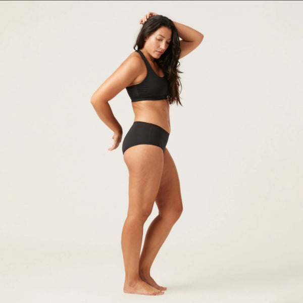 Vrouw in zwarte naadloze slip en sportbeha, zijaanzicht. Comfortabel ondergoed, ademend materiaal, perfecte pasvorm voor dagelijks gebruik.