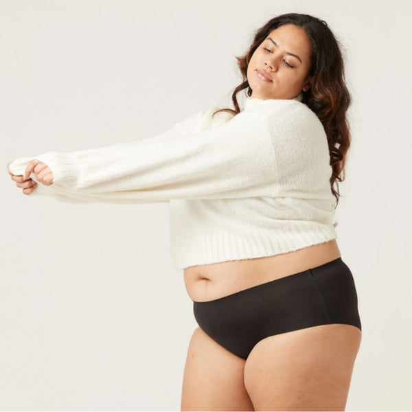 Vrouw in zwarte slip en witte trui, comfortabele damesmode, plus-size ondergoed, minimalistisch design, casual kledingstijl.