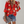 Vrouw in rode blouse met bloemenprint, denim short en luipaardprint clutch. Trendy damesmode, casual zomeroutfit, stijlvolle accessoires.
