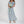 Vrouw in lange, lichtblauwe bloemenjurk met korte mouwen, houdt witte bloemen vast. Elegante zomerjurk, modetrend, casual chique stijl.