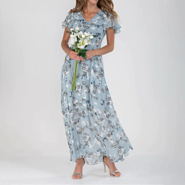 Vrouw in lange, lichtblauwe bloemenjurk met korte mouwen, houdt witte bloemen vast. Elegante zomerjurk, modetrend, casual chique stijl.
