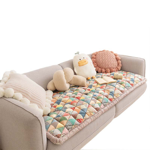 Beige bank met kleurrijke, katoenen beschermhoes en decoratieve kussens. Perfect voor woonkamerinrichting en bescherming van meubels.