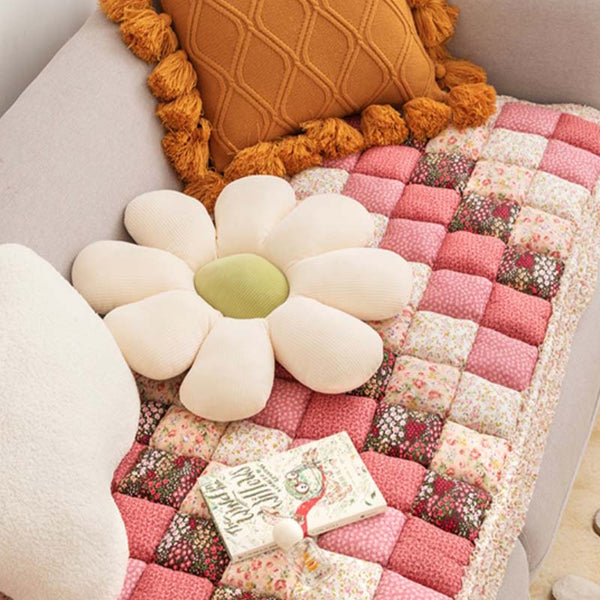 Katoenen bankhoes met bloemenpatroon, decoratieve kussens in bloemvorm en een boek op een beige bank. Perfect voor een gezellige woonkamer.