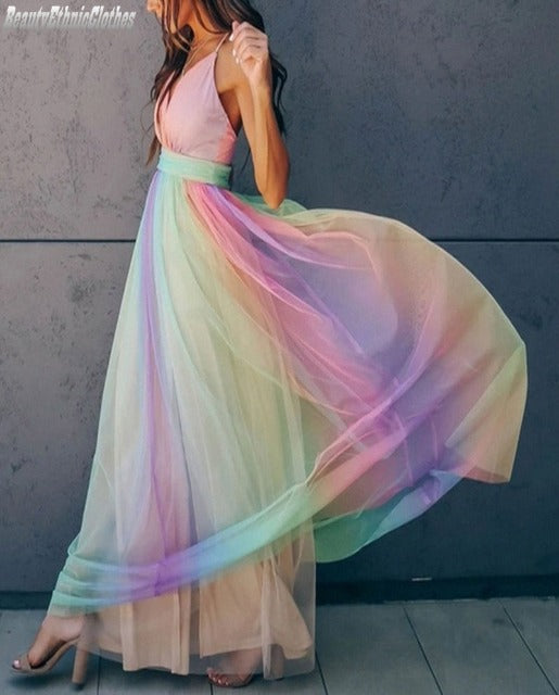 Vrouw in lange regenboogjurk met spaghetti bandjes, haltertop en vloeiende rok. Perfect voor zomerfeesten en gala's. Trendy damesmode.