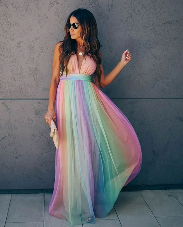 Vrouw in lange regenboogjurk met spaghettibandjes, haltertop en vloeiende rok, ideaal voor zomerfeesten en gala's. Trendy damesmode.