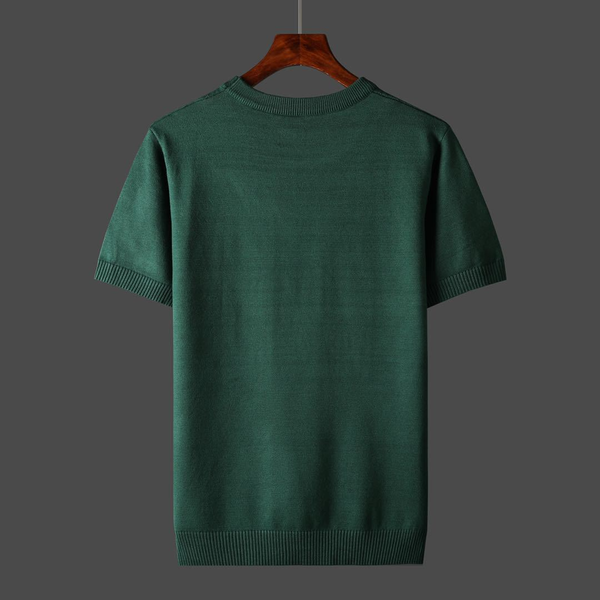 Groene katoenen trui met korte mouwen, effen ontwerp, op houten hanger tegen grijze achtergrond. Perfect voor casual en stijlvolle outfits.