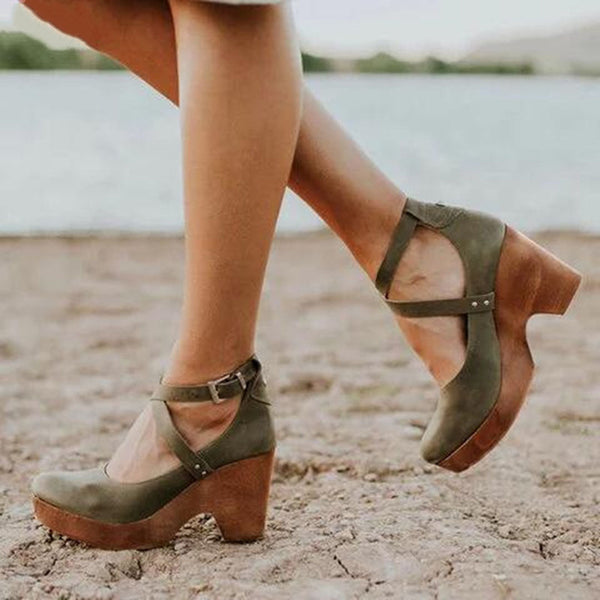 Groene damesklompen met houten hakken en kruisbandjes, gedragen op een strand. Modieuze zomerschoenen, comfortabel en stijlvol voor dagelijks gebruik.