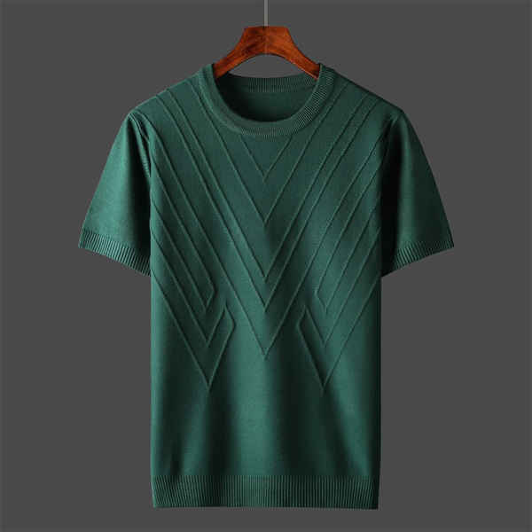 Groene gebreide trui met korte mouwen, geometrisch patroon, op houten hanger tegen grijze achtergrond. Stijlvolle herenkleding, casual mode.