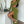 Vrouw in groene jurk met hoge split, poseert naast witte kast. Stijlvolle mode, trendy outfit, hoge hakken, moderne interieurstijl.
