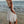 Vrouw in witte kanten zomerjurk op strand bij zonsondergang, golven op achtergrond. Perfecte strandoutfit, romantische jurk, zomermode.
