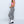 Vrouw in roze crop top en zwart-wit geruite broek, mode trendy outfit, witte laarzen, zijaanzicht, casual stijl, moderne kleding.