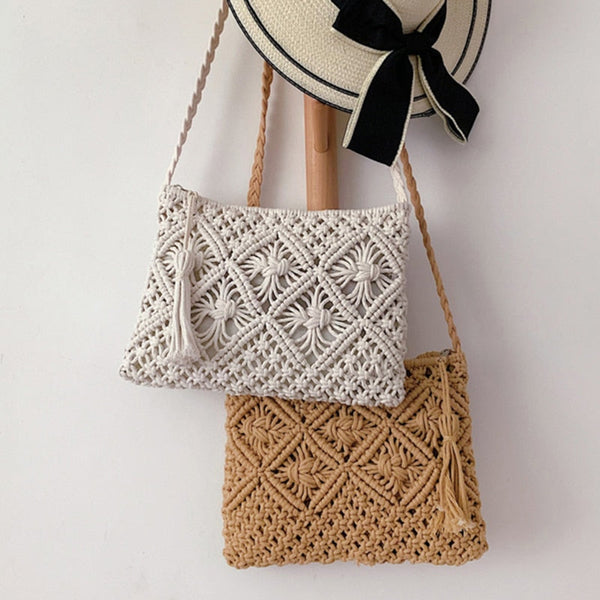 Twee handgemaakte macramé tassen, wit en beige, met bloemenpatroon, hangend aan een houten haak. Perfect voor zomerse boho-stijl outfits.