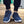Donkerblauwe sportschoenen met witte zolen, gedragen door persoon in zwarte broek. Comfortabele hardloopschoenen voor heren, ideaal voor dagelijks gebruik.