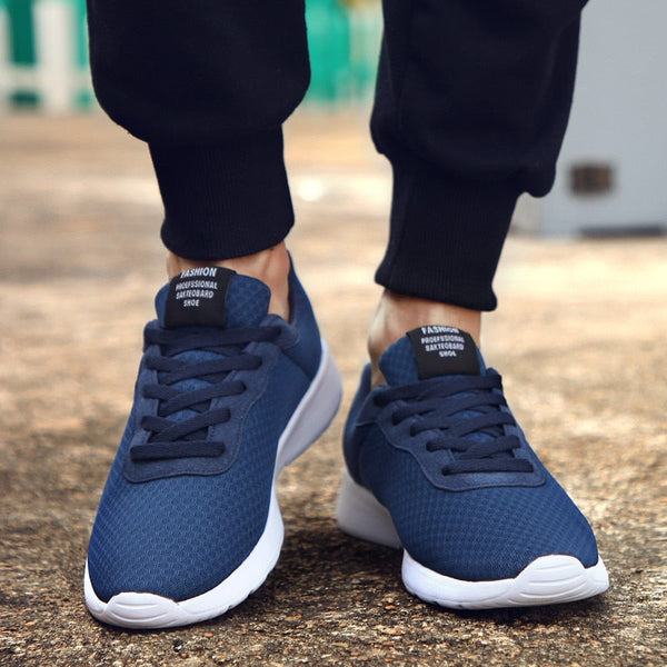 Donkerblauwe sportschoenen met witte zolen, gedragen door persoon in zwarte broek. Comfortabele hardloopschoenen voor heren, ideaal voor dagelijks gebruik.