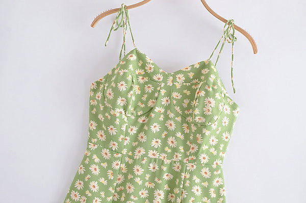 Groene zomerjurk met bloemenprint, spaghetti bandjes en hartvormige halslijn, hangend aan houten hanger. Perfect voor casual lente- en zomermode.