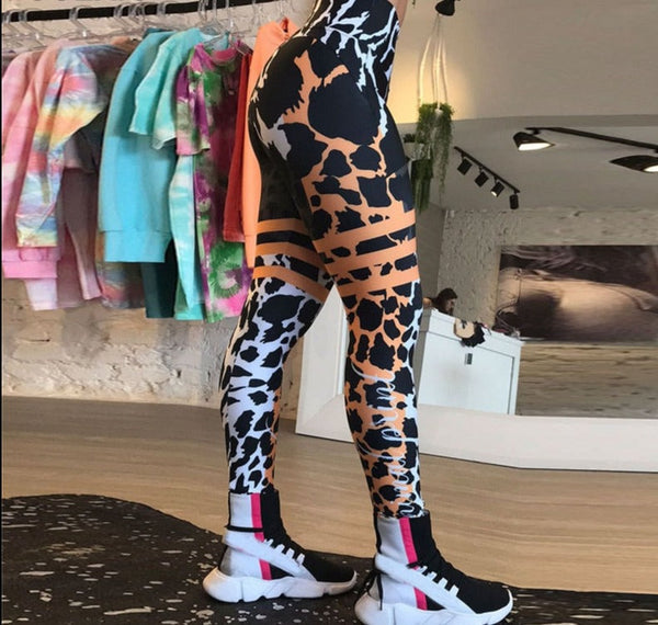 Dameslegging met zwart-wit dierenprint en oranje accenten, gedragen in een moderne boetiek. Comfortabele sportkleding, trendy mode.