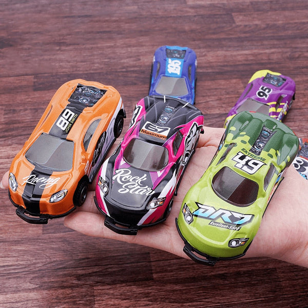Hand met vijf kleurrijke speelgoed raceauto's op houten vloer, inclusief oranje, roze, groene en paarse modellen. Geschikt voor kinderen, cadeau-idee.