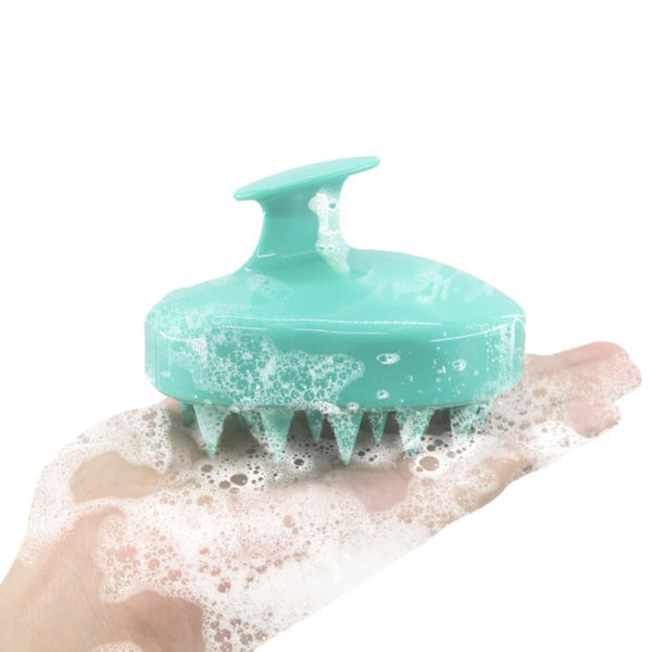 Turquoise siliconen hoofdhuidmassageborstel met handvat, schuimend in hand. Ideaal voor haarverzorging, hoofdhuidreiniging en ontspanning.