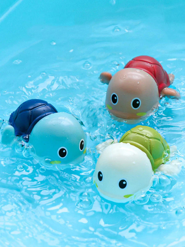 Drie kleurrijke schildpad badspeeltjes drijven in helderblauw water. Ideaal voor kinderen, badtijd, speelgoed, waterpret.