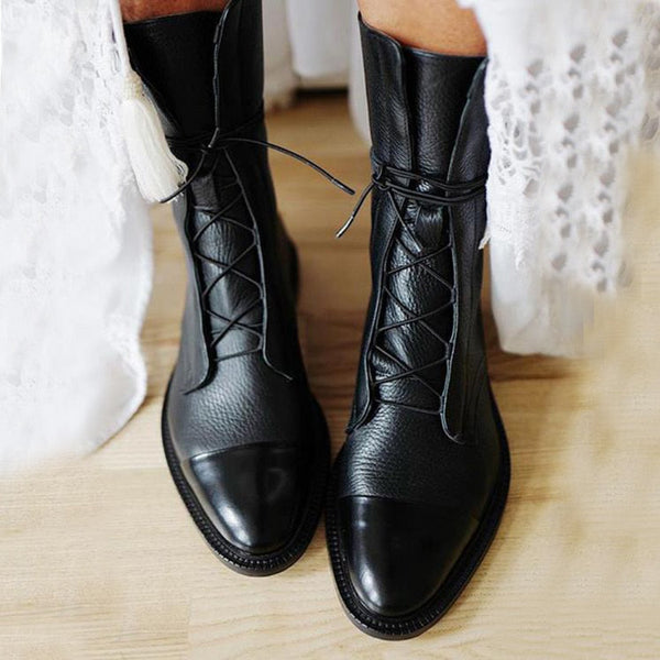 Zwarte leren veterlaarzen voor dames op houten vloer, modieuze enkellaarzen, stijlvolle schoenen, trendy herfst- en wintermode.