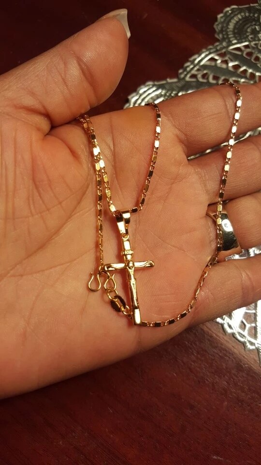 Gouden kruis ketting in hand, glanzend en gedetailleerd, op houten achtergrond. Perfecte sieradenkeuze voor stijl en elegantie.