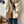 Vrouw in witte trui met zwarte strepen, draagt een bruine teddy schoudertas. Casual mode, herfstkleding, trendy accessoires, damesmode.