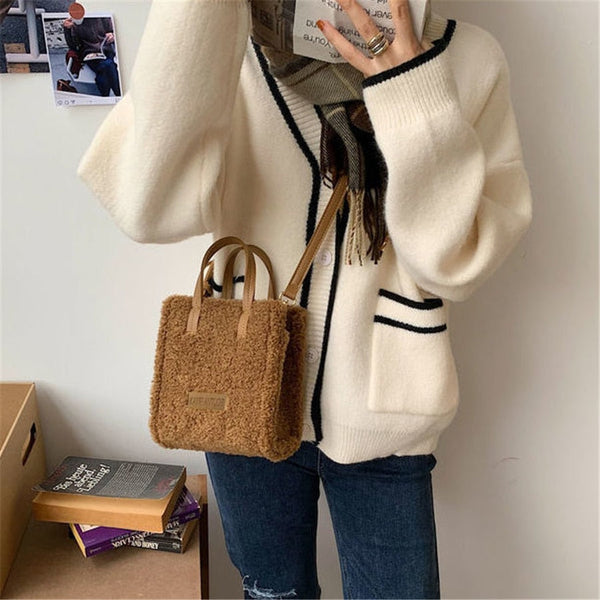 Vrouw in witte trui met zwarte strepen, draagt een bruine teddy schoudertas. Casual mode, herfstkleding, trendy accessoires, damesmode.