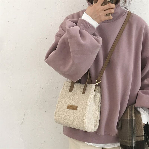 Vrouw met roze oversized trui en schapenvacht schoudertas. Modieuze winteroutfit, casual stijl, trendy accessoires, comfortabele kleding.