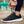 Zwarte sportschoen met witte zool, close-up van een persoon die de veters strikt. Casual en comfortabele sneakers voor dagelijks gebruik.