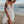 Vrouw in witte kanten zomerjurk met bloemenpatroon op strand bij zonsondergang, strandmode, elegante strandjurk, zomerkleding.