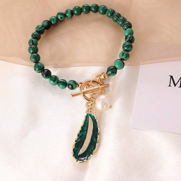 Groene malachiet armband met goudkleurige sluiting en parelhanger, elegant sieraad voor dames, handgemaakt, luxe accessoire, modieuze polsband.