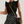 Vrouw in zwarte top met ruches, polkadot rok, bruine riem en ronde rieten tas. Trendy damesmode, zomeroutfit, casual chique stijl.